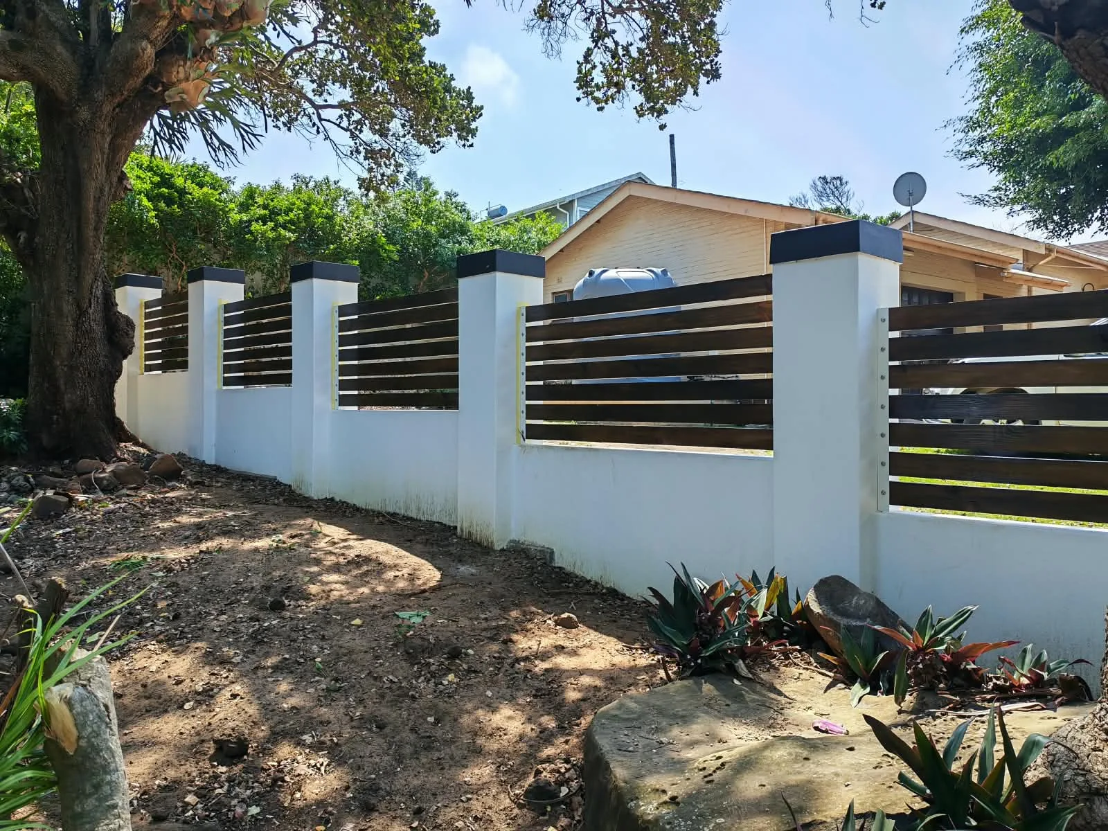 Timber-look boundary fence built between rendered pillars