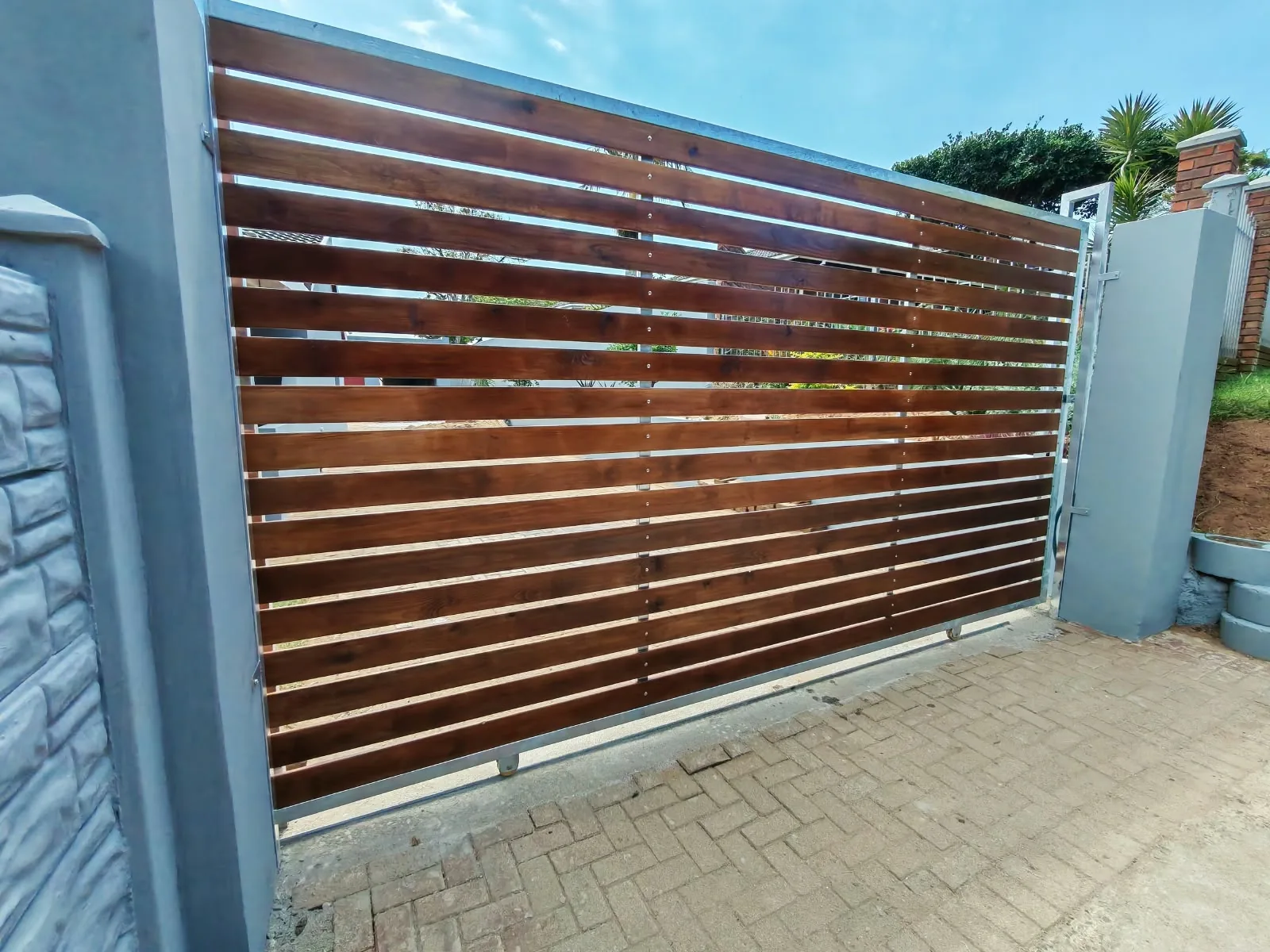 Custom timber-look sliding driveway gate with a galvanised steel frame